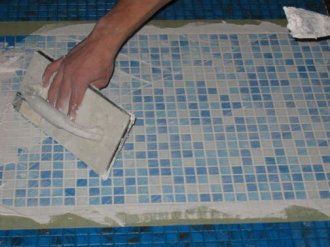 Процесс укладки мозаики в ванной